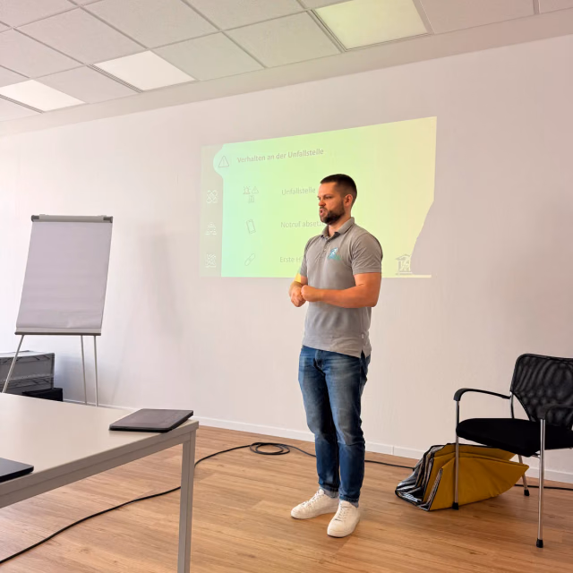 Ausbilder der Stadler Maidau Akademie erklärt vor Flipchart und Beamer die Inhalte des Erste-Hilfe-Kurses